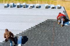 Roofing crew installing asphalt shingles on a residential roof