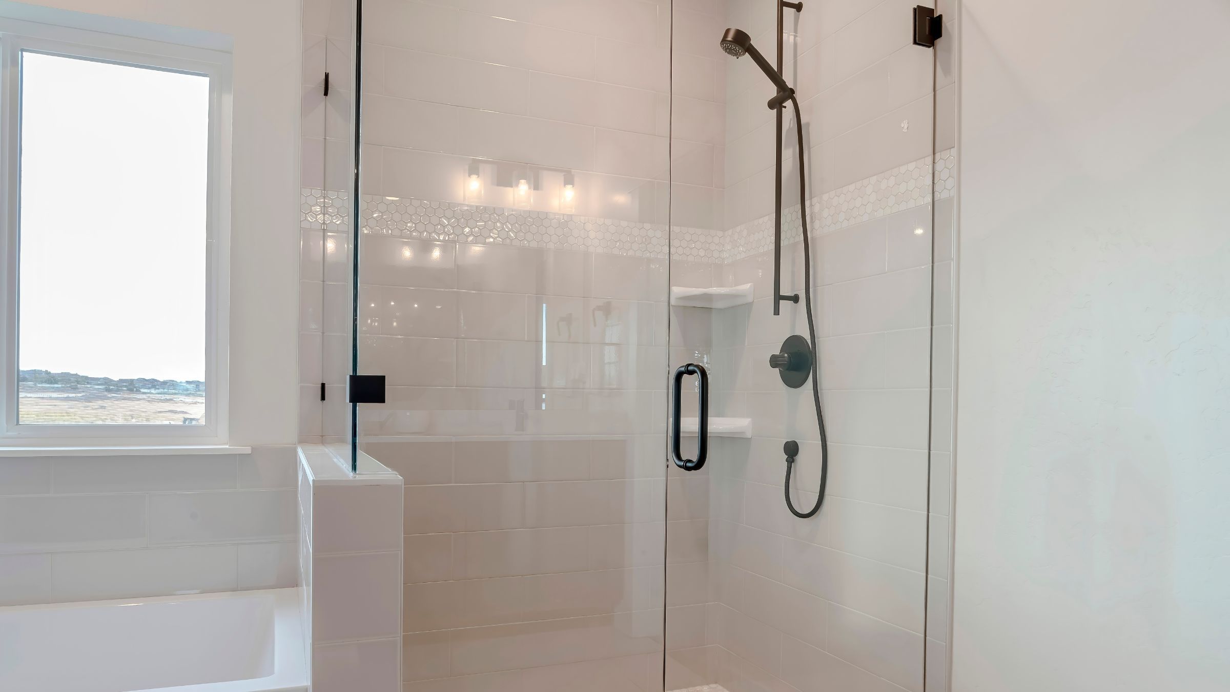 Frameless glass shower door with minimal hardware in a tiled bathroom