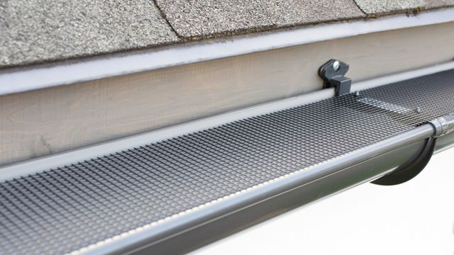 Micro-mesh gutter guard fastened along the edge of a shingled roof