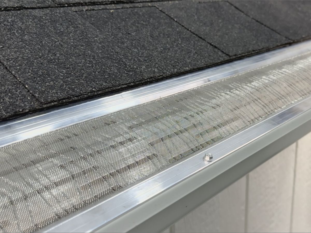 Close-up of a micro-mesh gutter guard fastened along a shingled roof edge