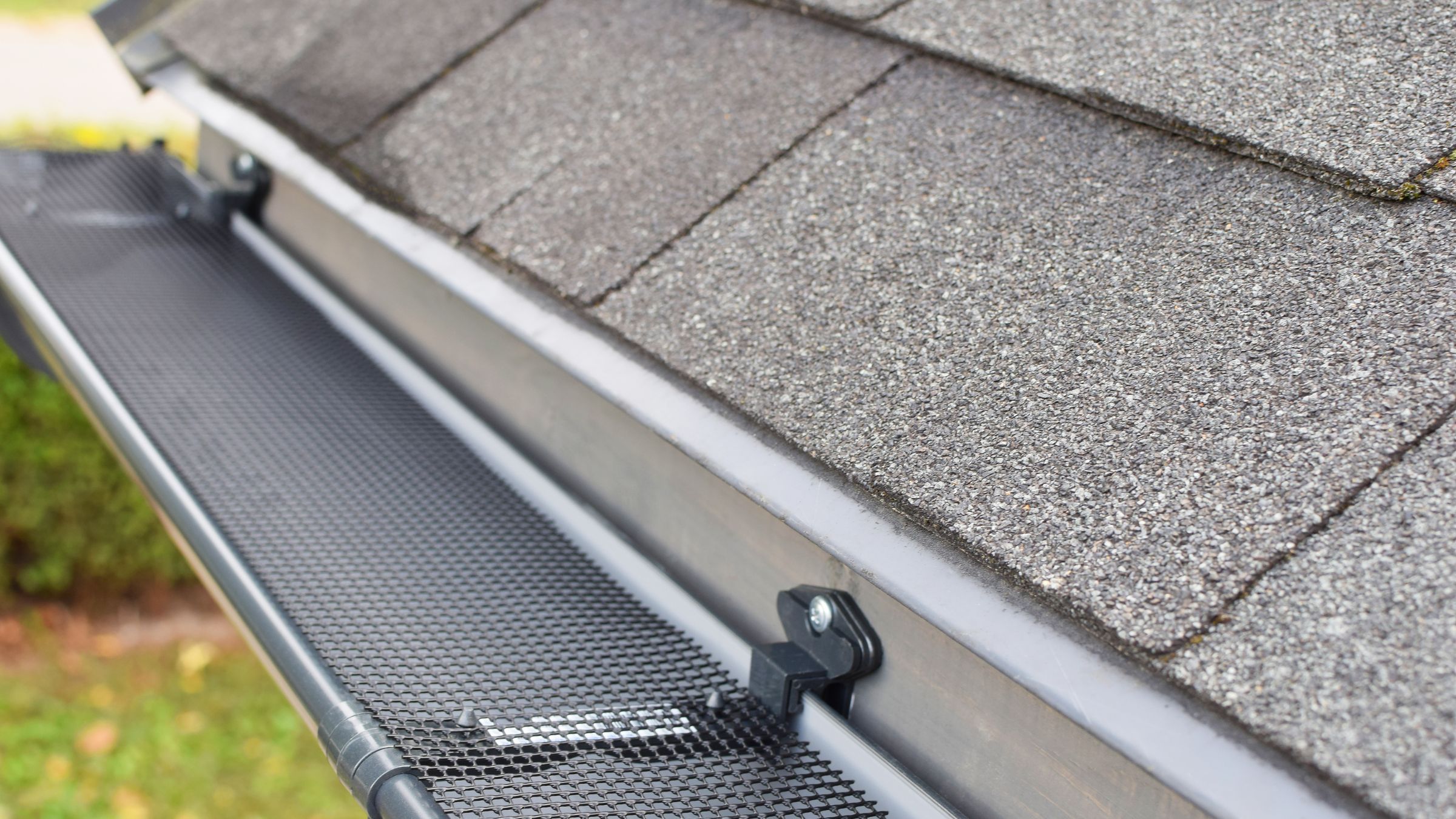 Micro-mesh gutter guard fitted over a K-style gutter along a shingled roof edge