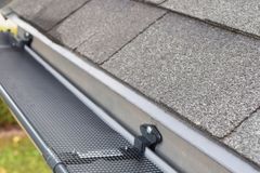 Micro-mesh gutter guard fitted over a K-style gutter along a shingled roof edge