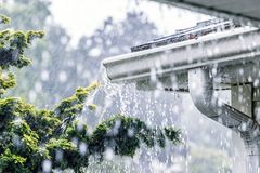 Rainwater spilling over the front edge of a gutter during heavy rain