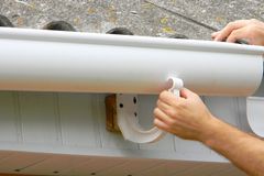 Half-round gutter being fitted into an external bracket on the fascia