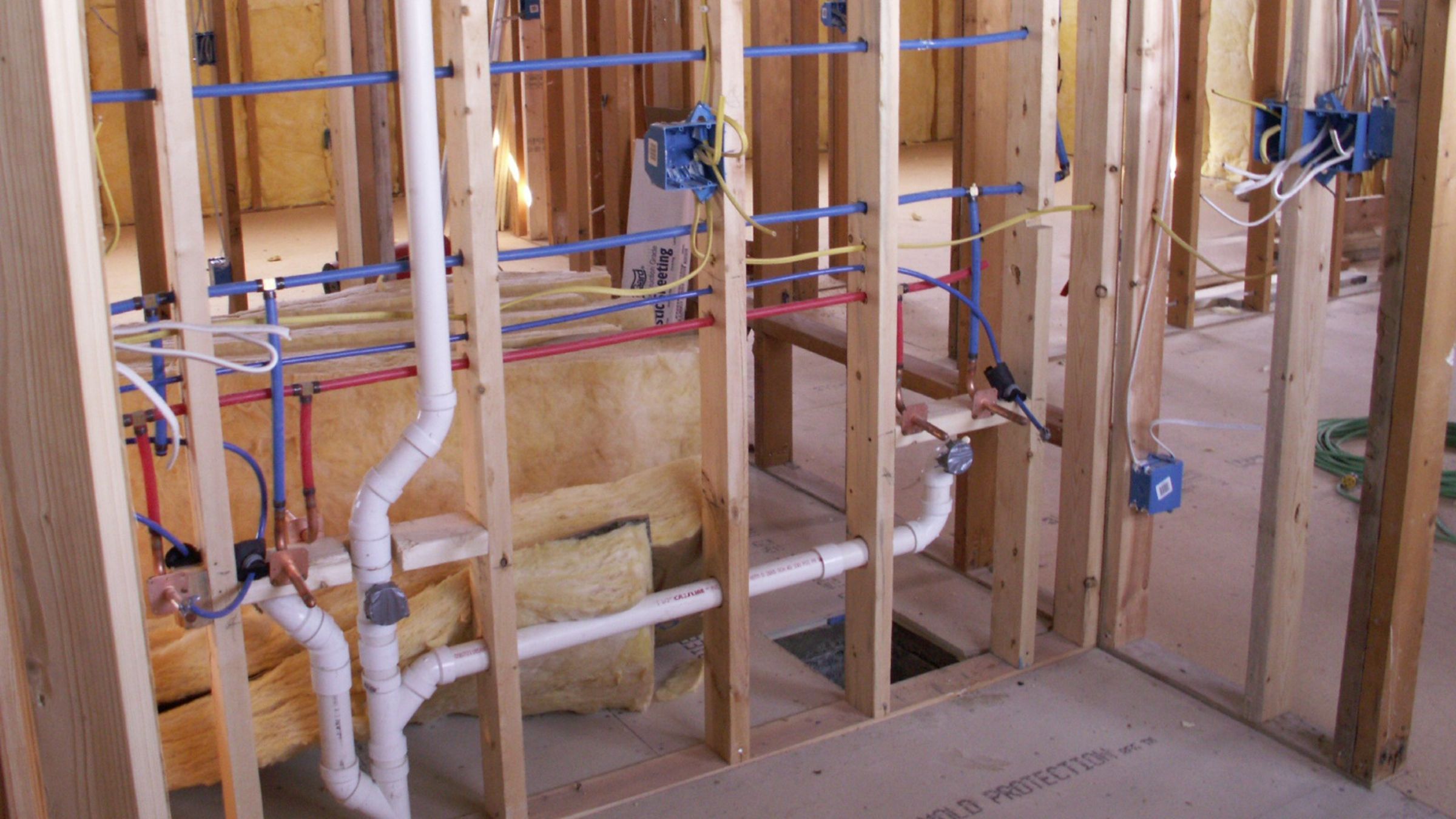 Open bathroom wall and floor showing plumbing rough-in during a remodel