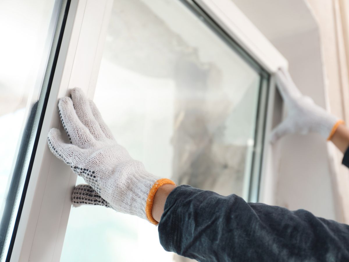 Gloved hands setting a new window unit into the wall opening