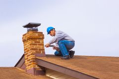 Metal step flashing where a brick chimney meets a shingled roof