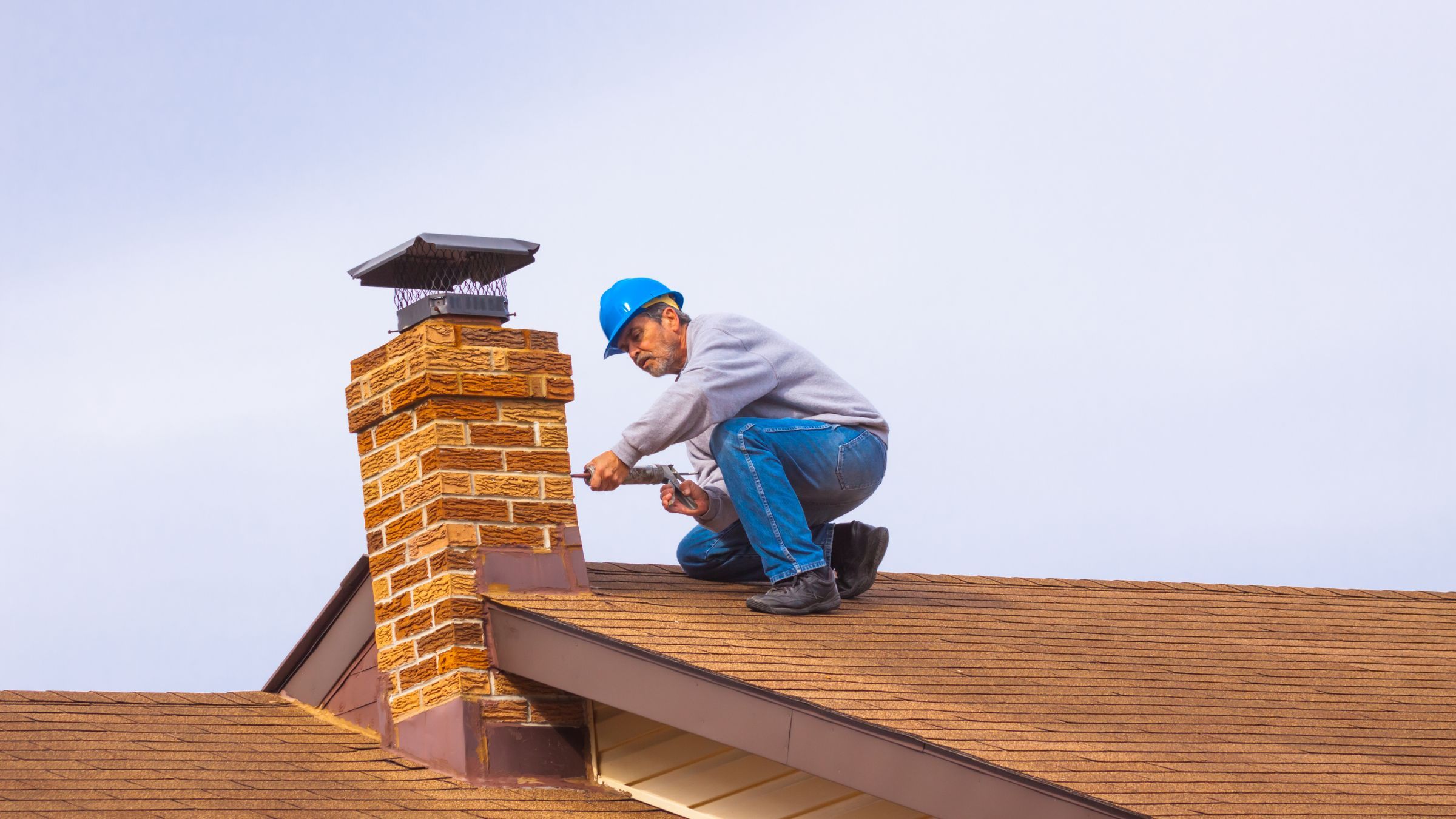 Metal step flashing where a brick chimney meets a shingled roof