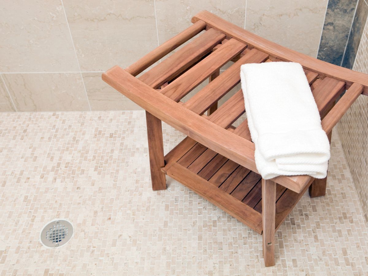 Tiled walk-in shower floor with a centre drain and a teak shower bench