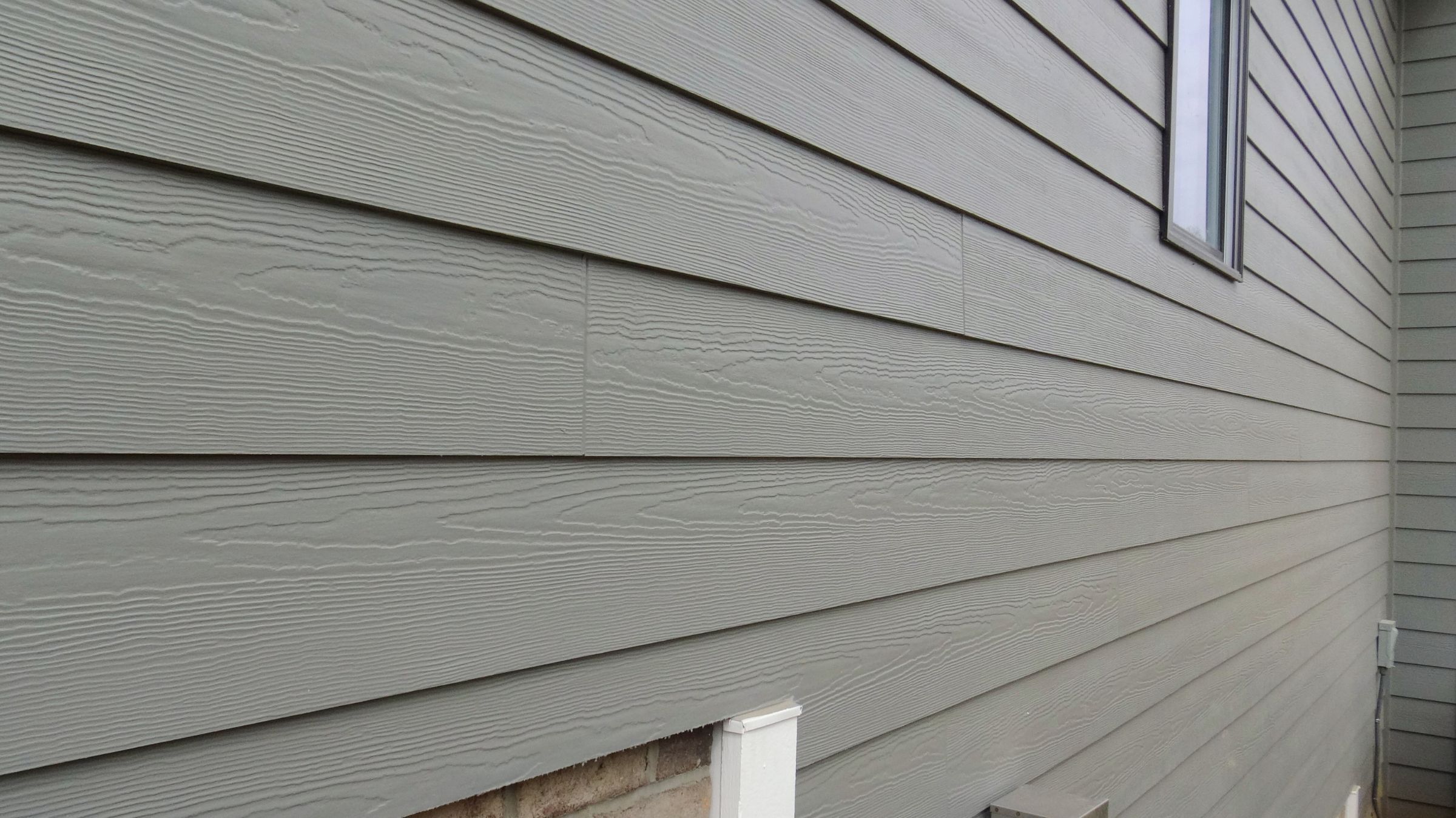 Fiber cement lap siding with visible woodgrain texture on a house wall