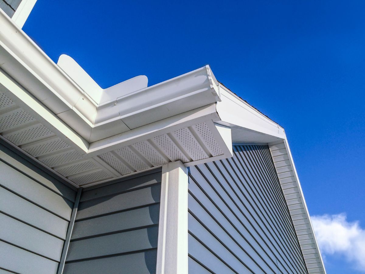Vented soffit, fascia and gutter meeting a sided wall at the roof edge