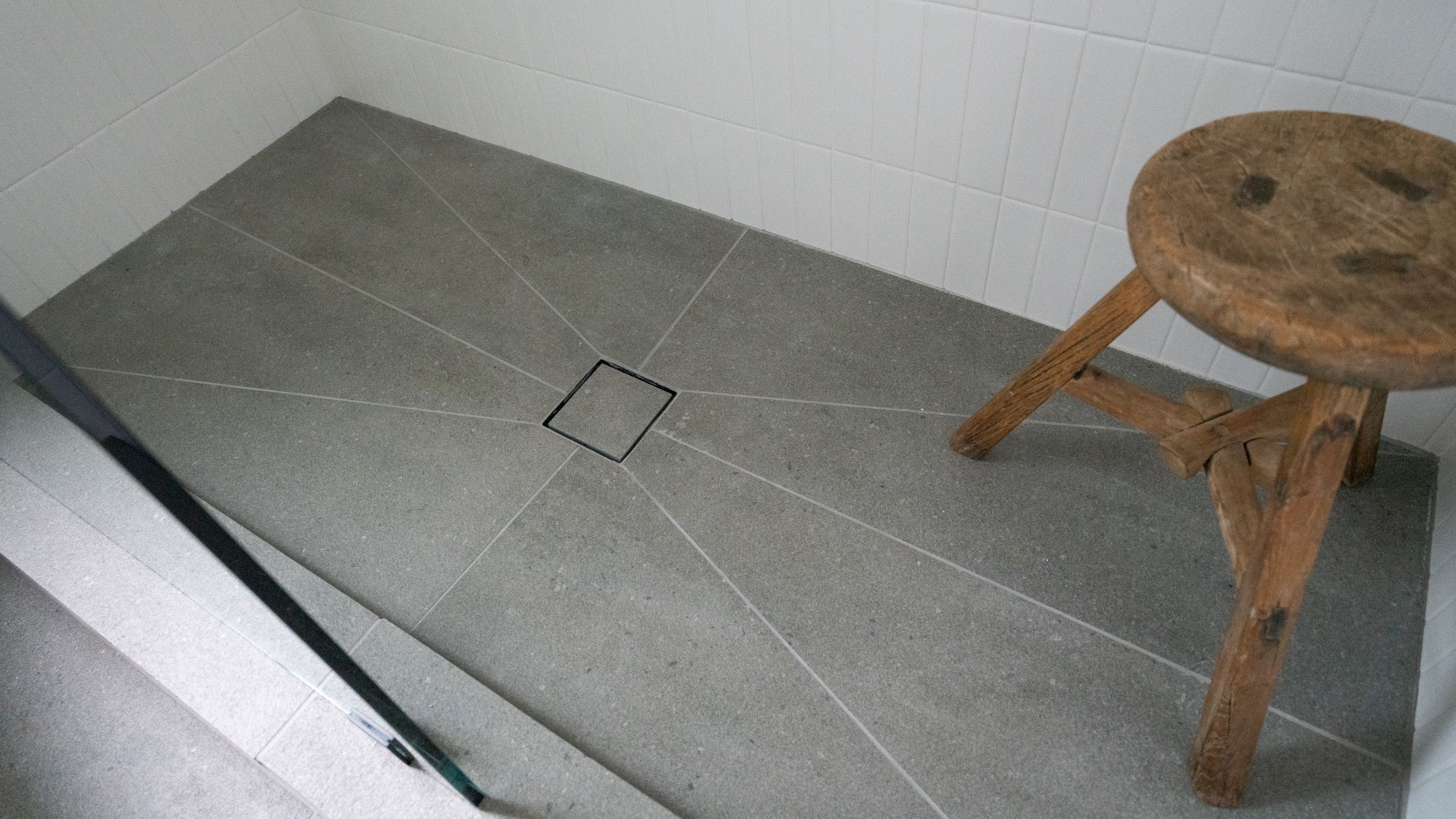 Tiled walk-in shower with a central point drain and a low entry step