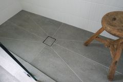 Tiled walk-in shower with a central point drain and a low entry step
