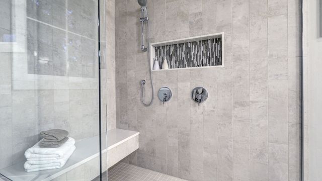 Modern tiled walk-in shower with a glass panel and recessed niche