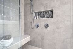 Modern tiled walk-in shower with a glass panel and recessed niche