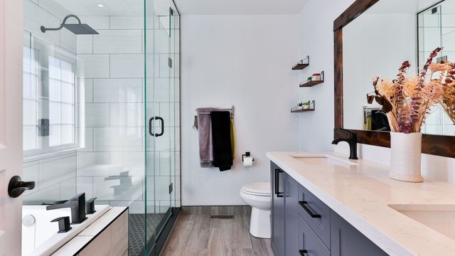 Bathroom with a glass-enclosed walk-in shower, white marble-look tile and a dark double vanity