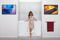 Walk-in tub with its door open beside a tiled bathroom wall