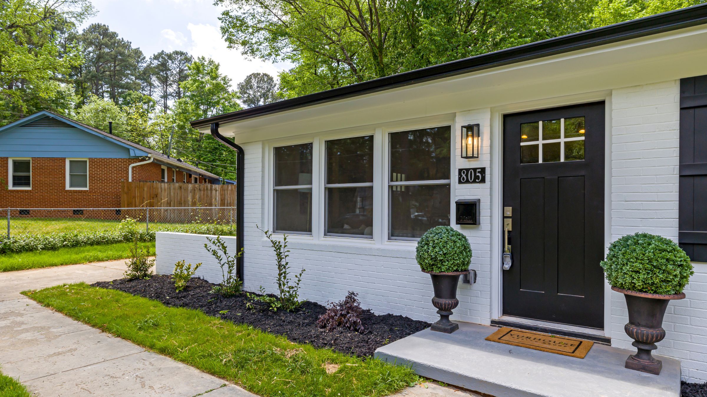 White brick home with a bank of three double-hung windows beside a dark front door